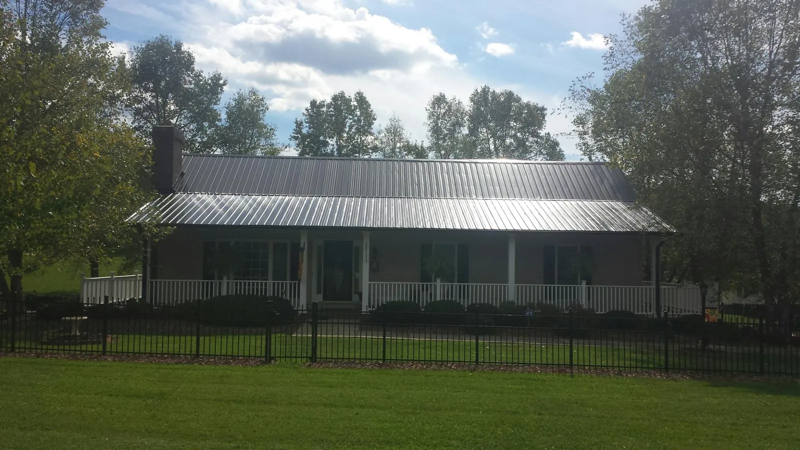 Gray metal roof on a brick ranch with a full width front porch — Gutter Guard Installation work by our crew in Newcastle